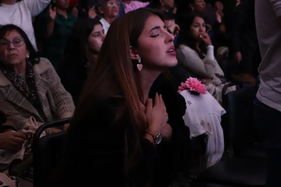 Joven adorando con los ojos cerrados durante un culto
