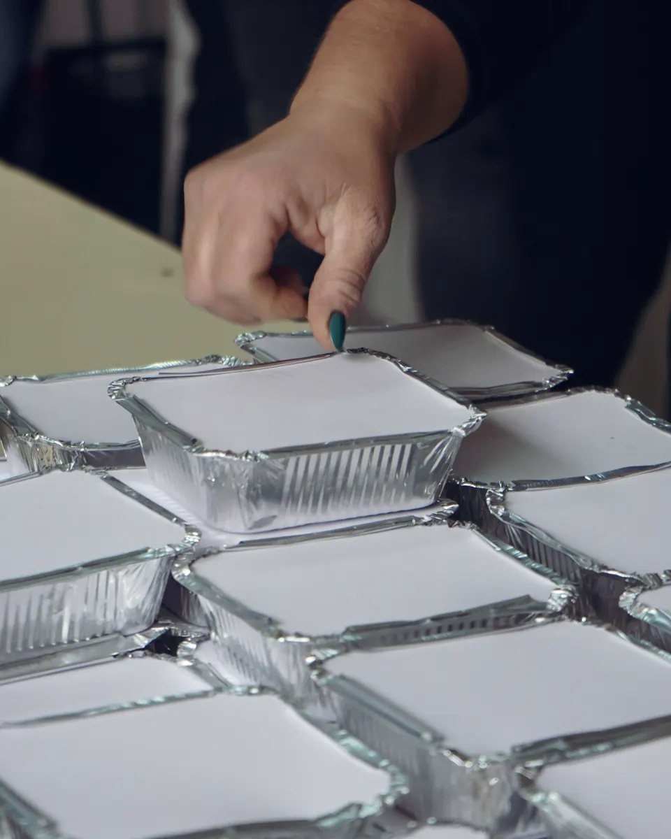 Voluntarias con guantes preparan bandejas de almuerzo selladas en el Comedor Abierto de Pudahuel
