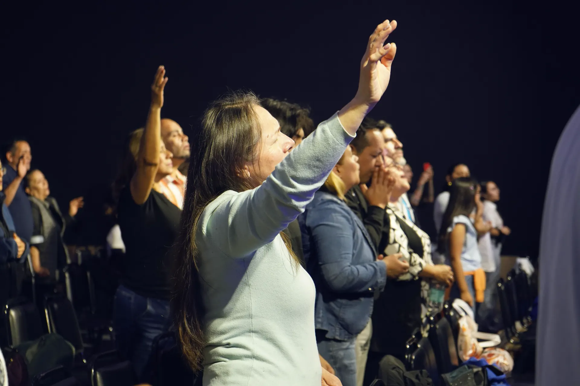Congregación de la Iglesia Cristo es Vida adorando con las manos alzadas durante el culto