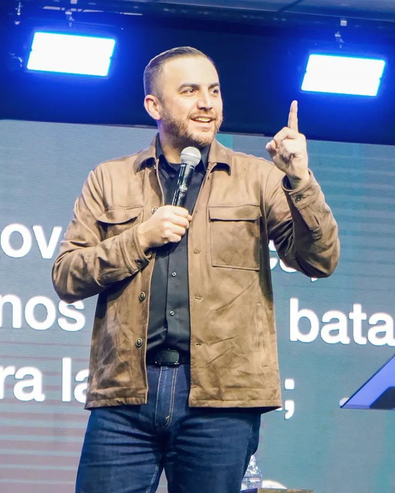 Pastor Emanuel Herrera predicando con un micrófono en el escenario de la Iglesia Cristo es Vida